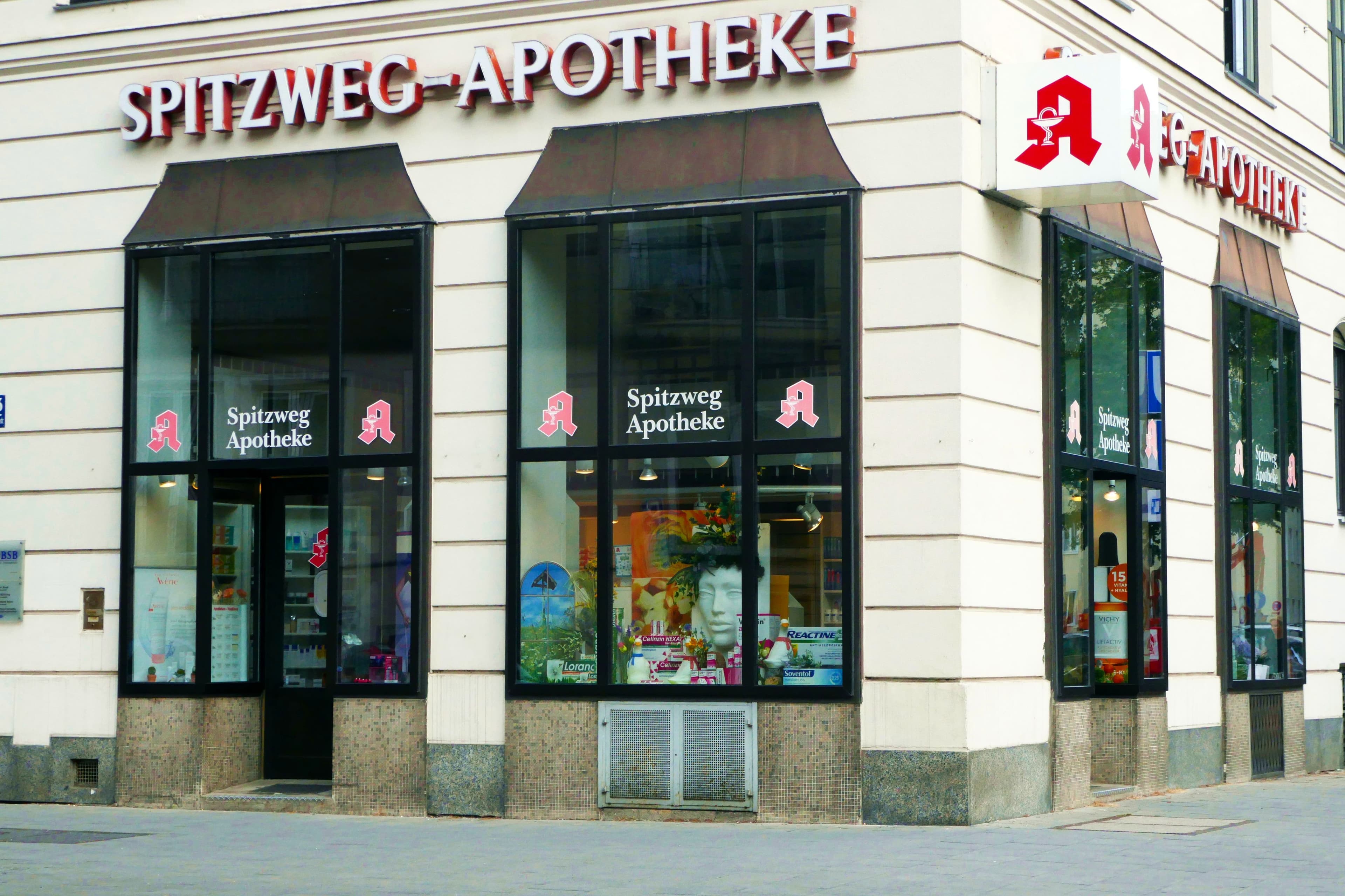 Die Spitzweg Apotheke an der Ecke Hohenzollernstraße: heller Altbau mit Schaufenstern und rotem Apotheken-A.