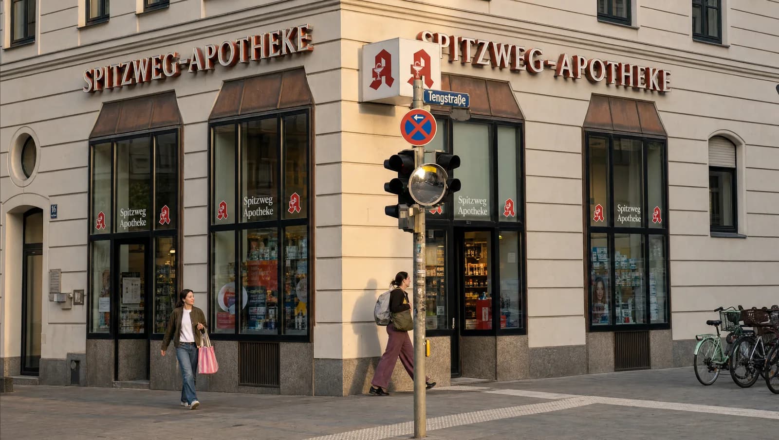Die Spitzweg Apotheke an der Ecke Hohenzollernstraße und Tengstraße: heller Altbau mit Schaufenstern, rotem Schriftzug und Apotheken-A.